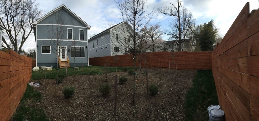 "Before" image of blue-gray two-story home's fenced backyard.