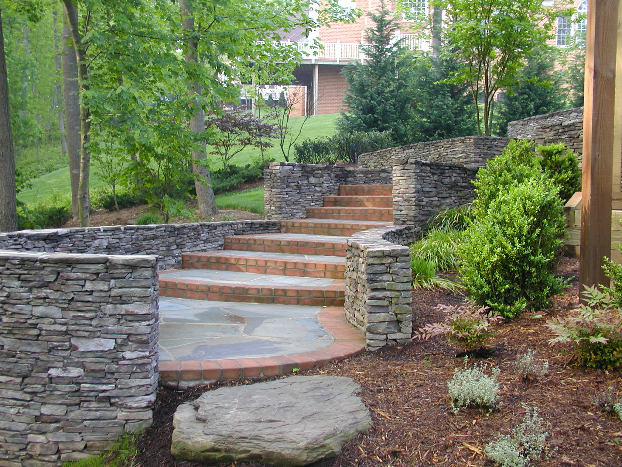 Outdoor stone staircase with surrounding plant and mulch bed