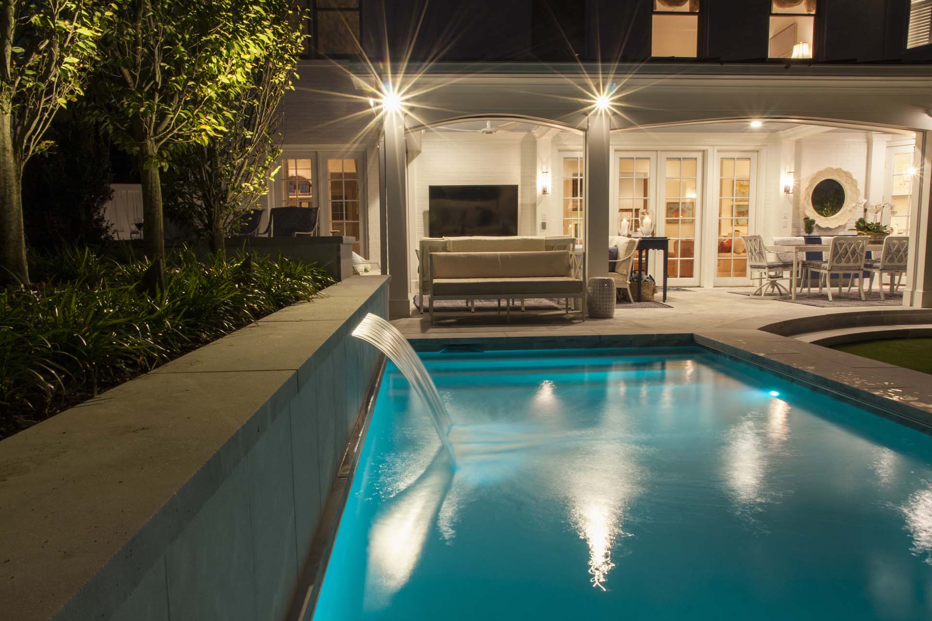 A house with a pool and a fountain, enhanced by landscape lighting, creating a captivating visual ambiance.