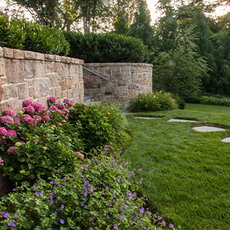 Front yard Landscaping with Bushes, Flowers, and Trees with a retaining Wall