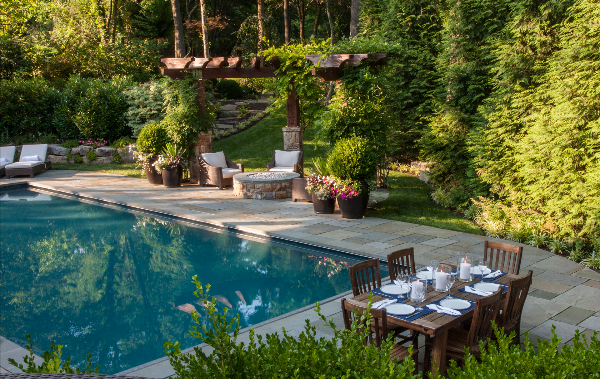 Pool in Backyard with Outdoor Furniture, Fire Place, Flowers, and Bushes