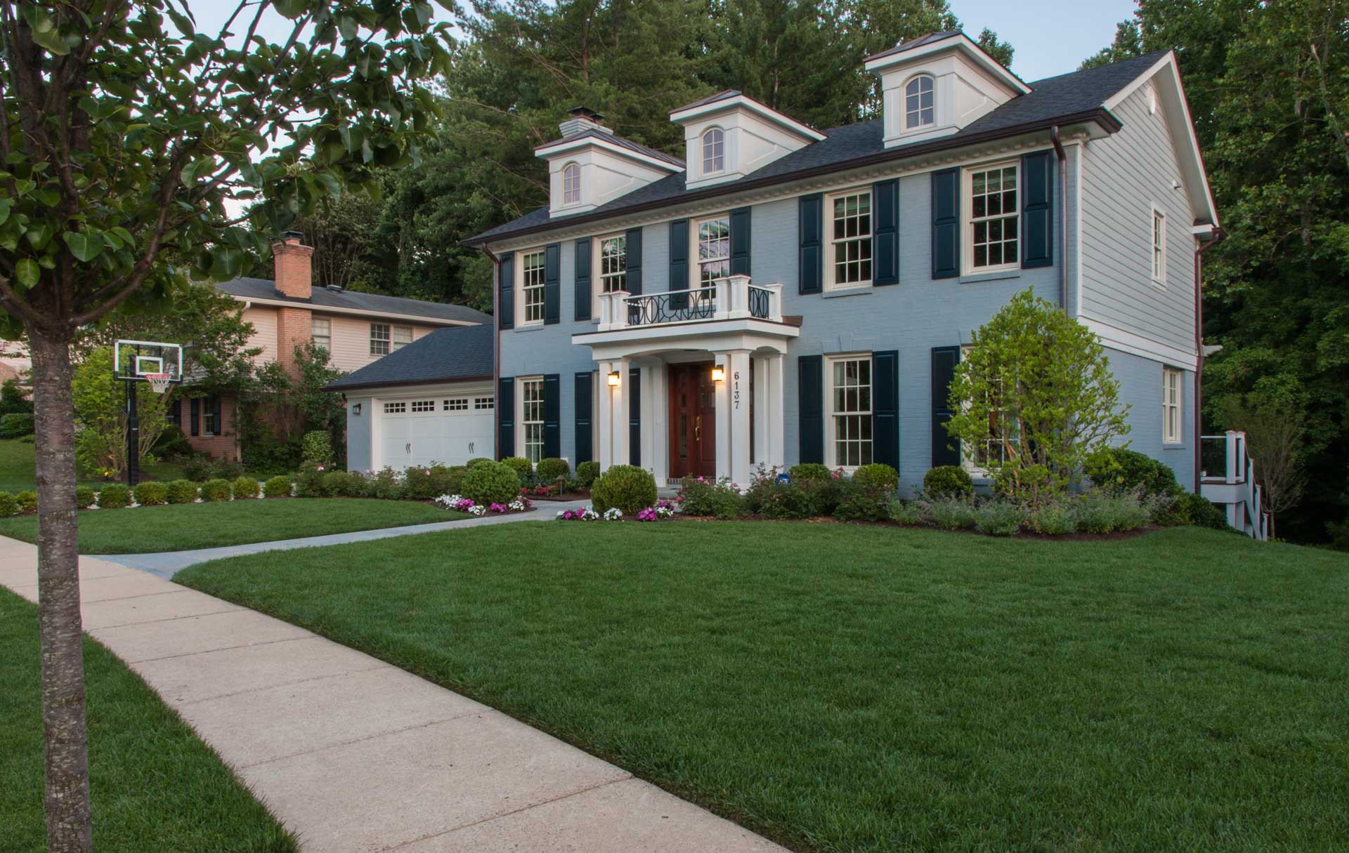 A spacious blue house with a driveway and well-maintained lawn in front.