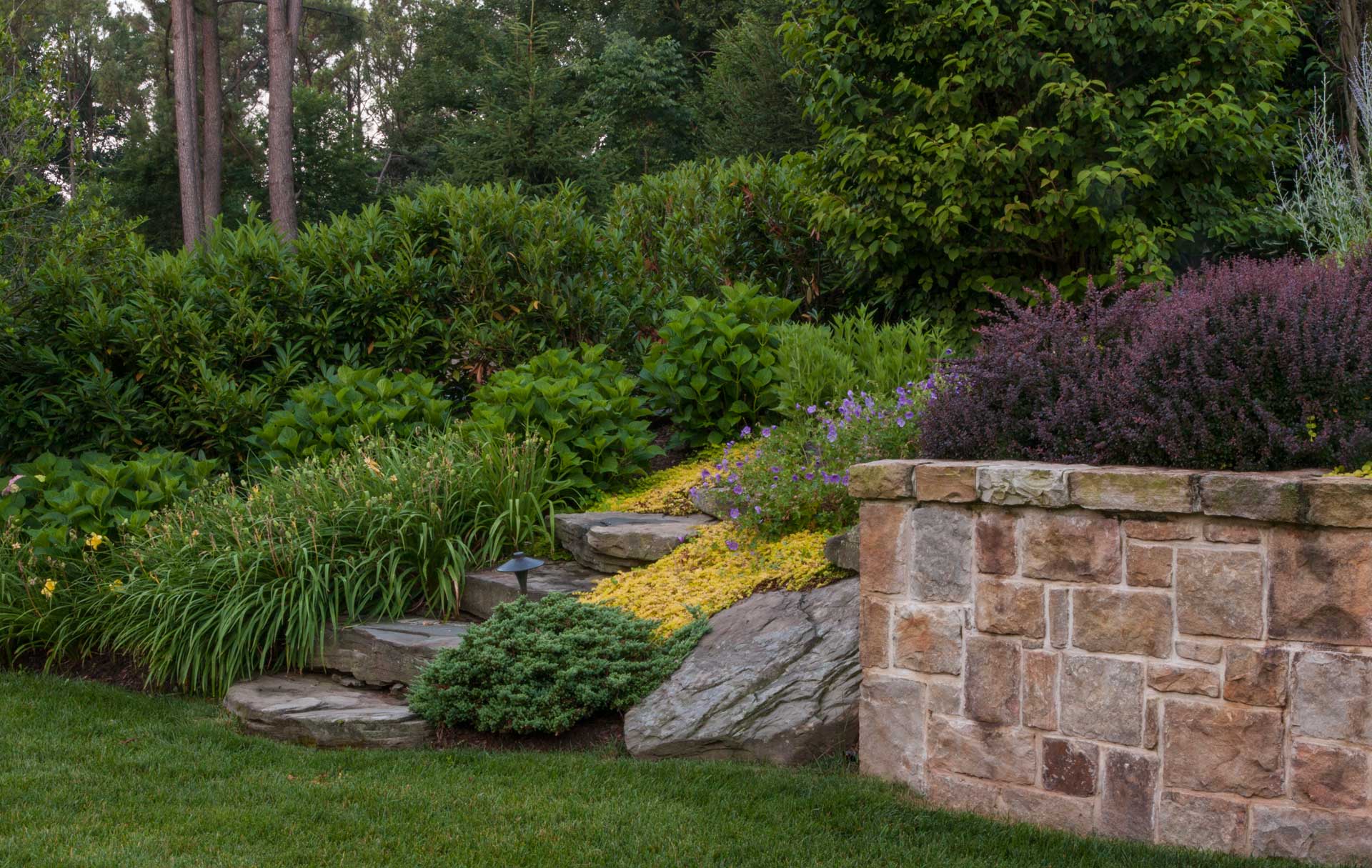 A picturesque stone retaining wall adorned with vibrant plants and flowers.