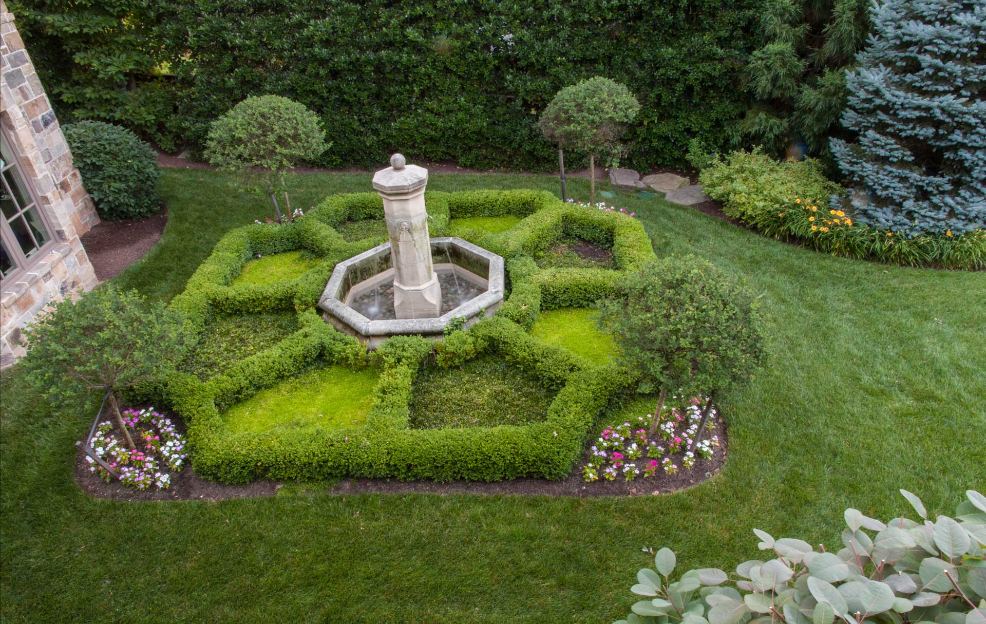 A serene circular landscaped garden with a beautiful fountain and lush trees, creating a tranquil oasis.