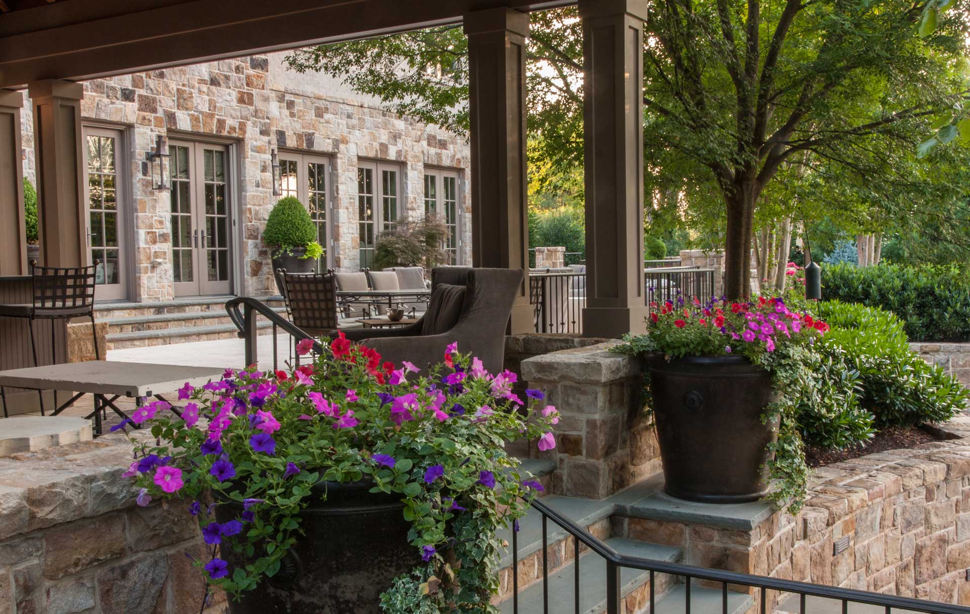Colorful potted flowers adorn a stone wall on a charming patio.