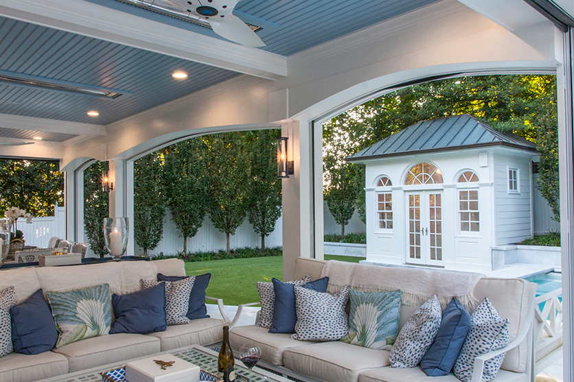 Outdoor covered patio area with two gray couches and blue pillows.