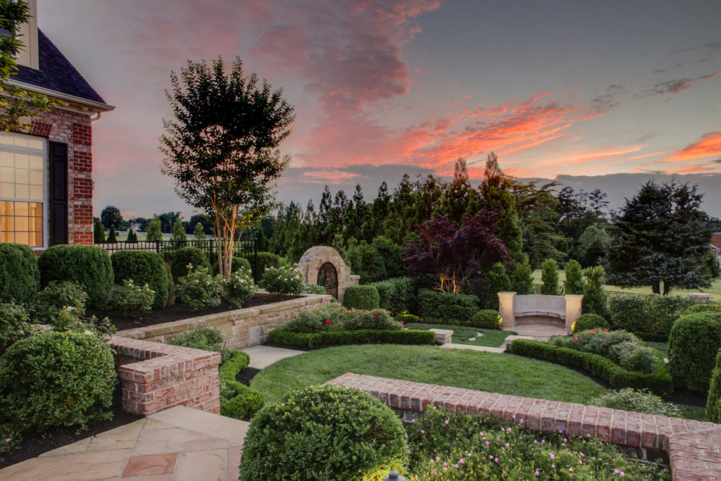 Large well-manicured yard with stone walkways, at sunset.