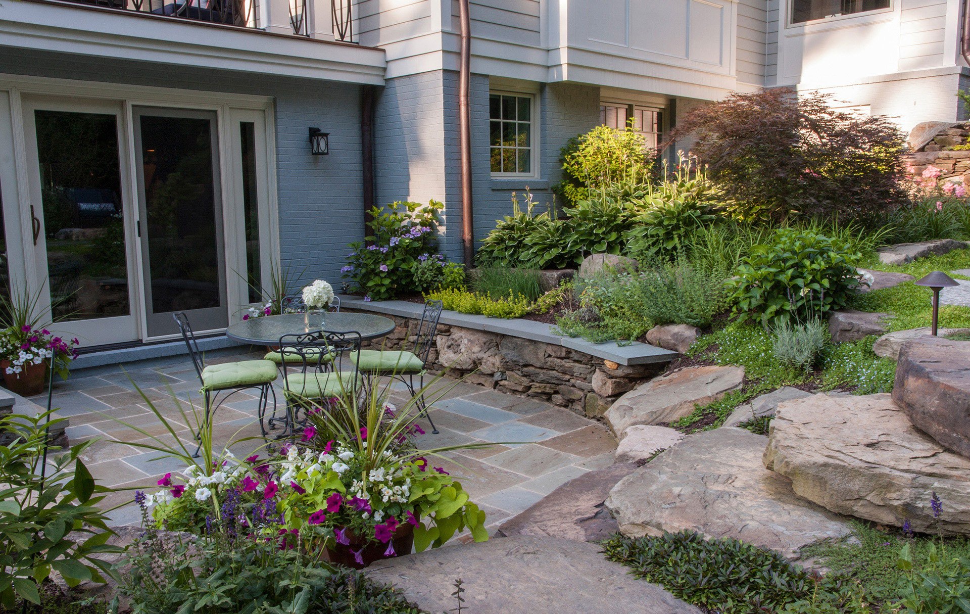 A picturesque outdoor space with a hot tub and patio furniture, bordered by a beautiful stone wall.