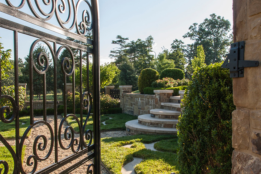 A stone walkway leading to a garden gate with a retaining wall. 