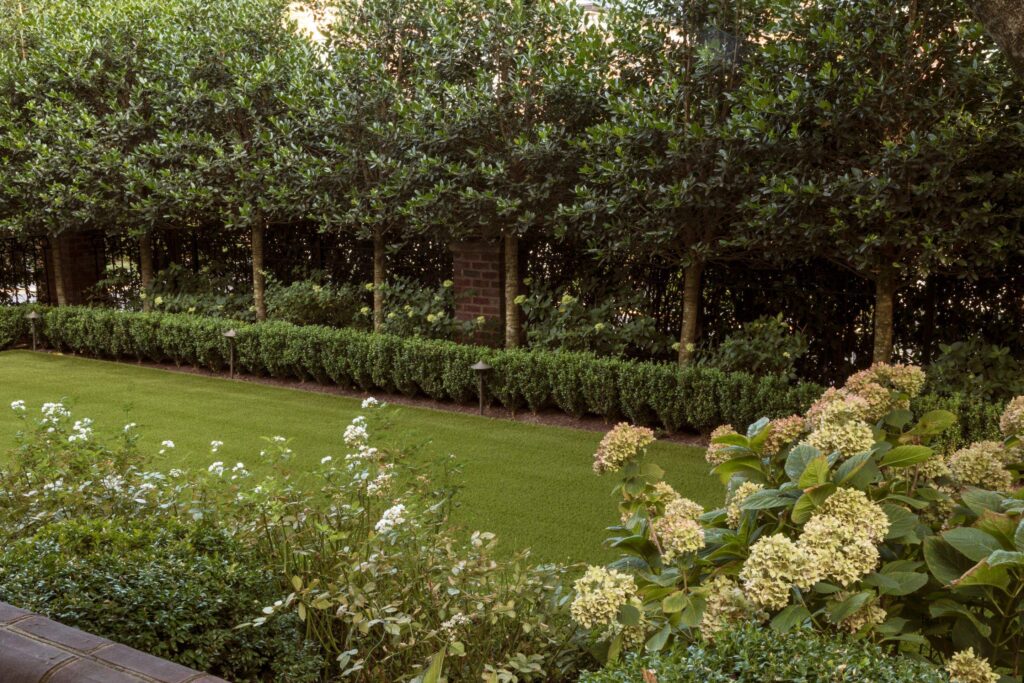 A beautifully manicured lawn with flowers blooming and bushes along the perimeter